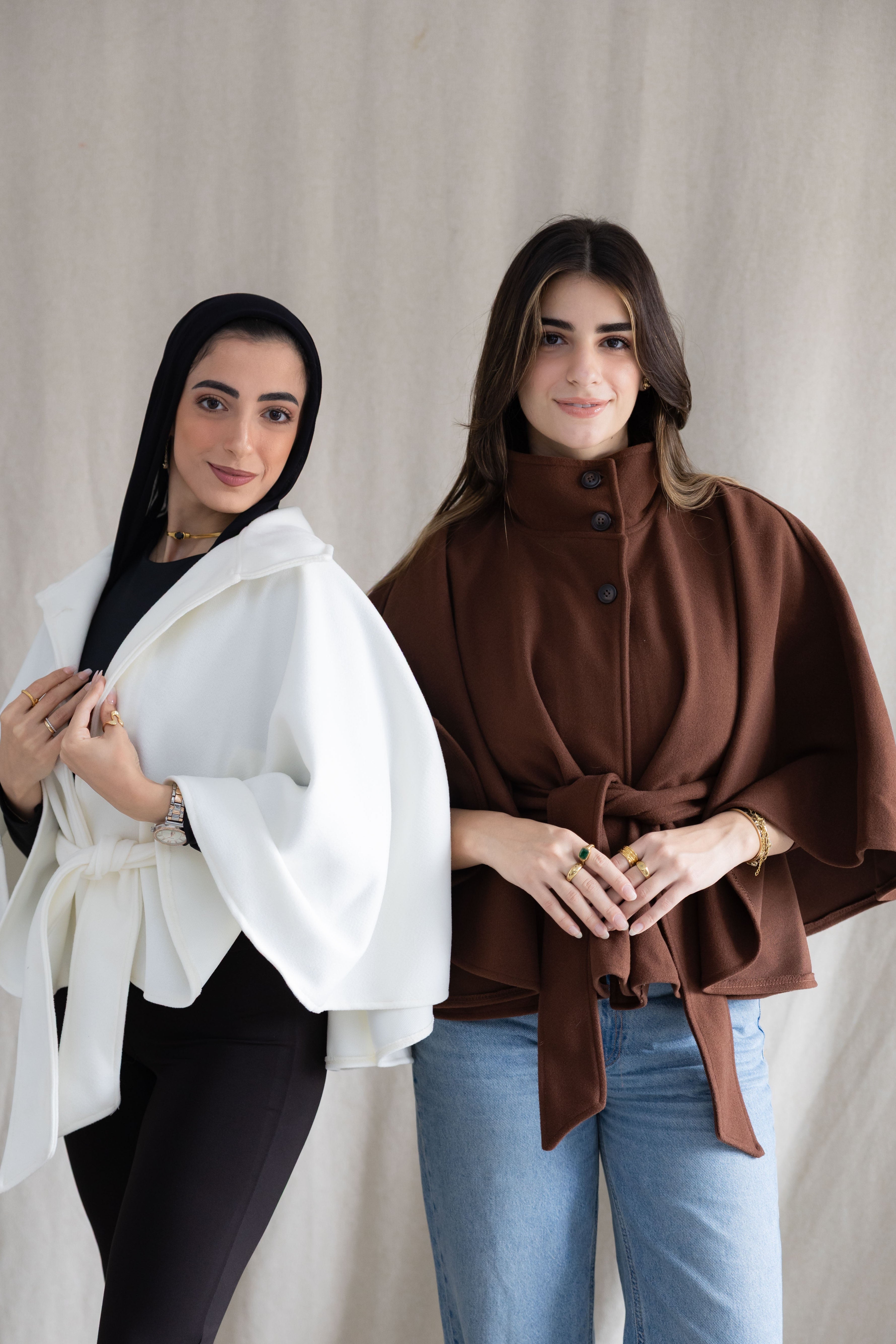 Two women wearing shawls over their shoulders against a neutral background